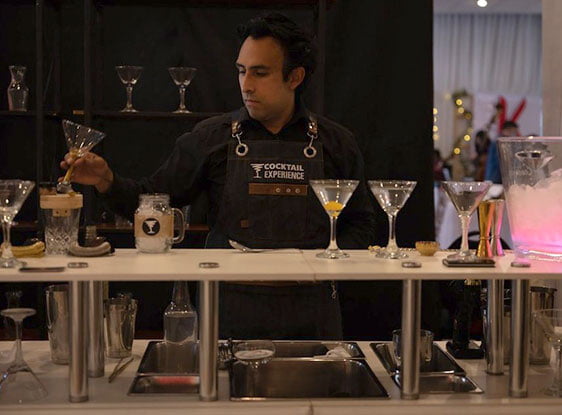 Dani Morales agarrando una copa coctel detras de una barra en evento en La Paz