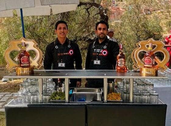 Dos bartenders posando detras una barra negra en un evento corporativo